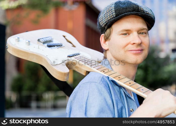 Young musician with guitar in city. Portrait of young musician with guitar in city