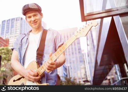 Young musician with guitar in city. Portrait of young musician with guitar in city