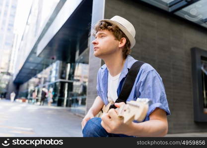 Young musician with guitar in city. Portrait of young musician with guitar in city