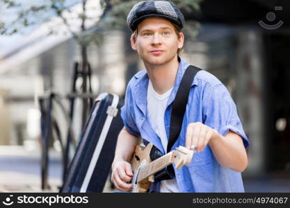 Young musician with guitar in city. Portrait of young musician with guitar in city