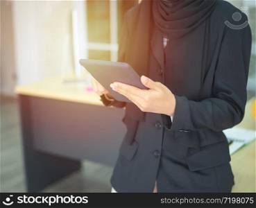 Young muslim asian female businesswoman using graphics tablet while working with computer at studio or office.