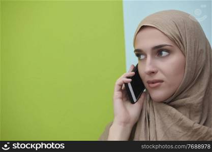 Young muslim businesswoman in traditional clothes or abaya talking on the smartphone. Arab woman  in front of black chalkboard and representing techology, islamic  fashion and Ramadan kareem concept
