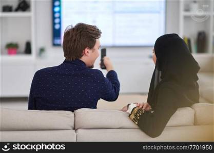 Young muslim couple enjoing time together at home during Ramadan. Happy arabic family watching TV