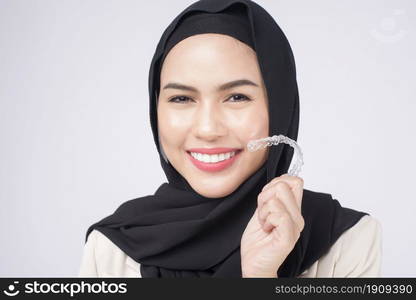 Young muslim woman holding invisalign braces in studio, dental healthcare and Orthodontic concept.