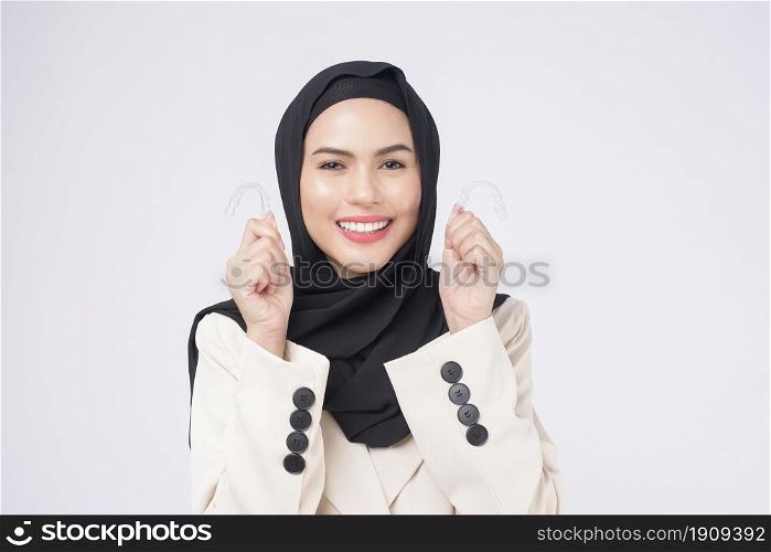 Young muslim woman holding invisalign braces in studio, dental healthcare and Orthodontic concept.