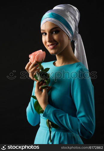 Young muslim woman in blue dress with rose flower