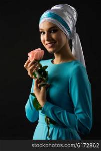 Young muslim woman in blue dress with rose flower