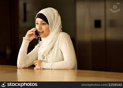 Young Muslim woman talking on cellphone.