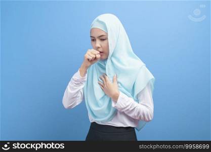 Young muslim woman with hijab  feeling sick and coughing over blue background studio.  