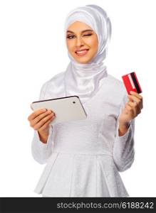 Young muslim woman with tablet PC and plastic card isolated