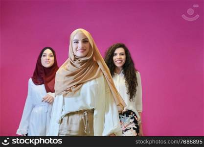 Young muslim women posing on pink background. Happy and pretty girls two wearing hijab representing Ramadan concept