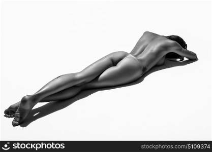 Young naked woman laying on white floor. Perfect skin. Black and white photograph