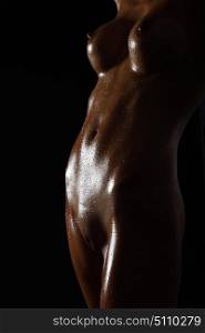 Young naked woman posing on black background. Perfect skin. Epilated female