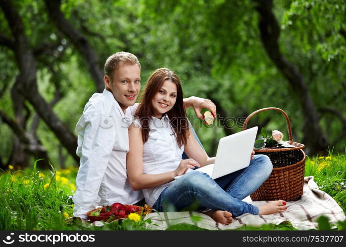 Young nice couple with the laptop in forest