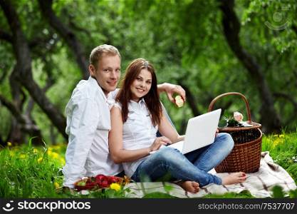 Young nice couple with the laptop in forest