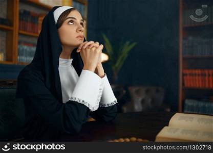 Young nun in a cassock prays crossed her arms. The sister in the monastery, religion and faith, religious people. Young nun in a cassock prays crossed her arms