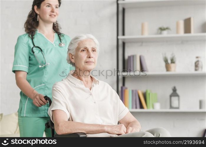 young nurse assisting disabled senior woman sitting wheel chair