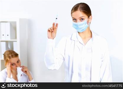 Young nurse with syringe doing vaccination in office