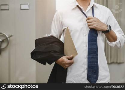 Young office walking holding a suit jacket, removing necktie