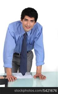 Young office worker leaning on his desk