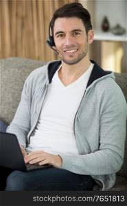 young operator of call center with head-phones work with laptop