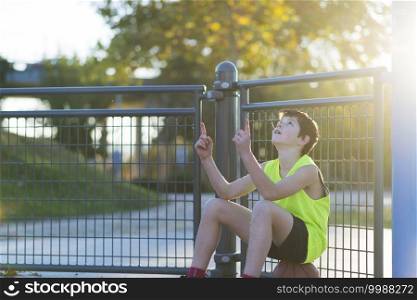 young outdoors sitting on basket ball at a street court with ball
