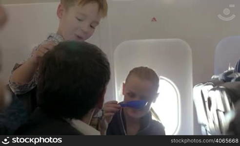 Young parents and child having fun during the flight. Boy playing with paper plane and then with fathers hand, mother playing with spades