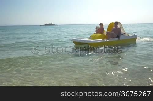 Young parents and little child having water ride in pedal boat. Mother taking selfie with pad. Family summer holidays