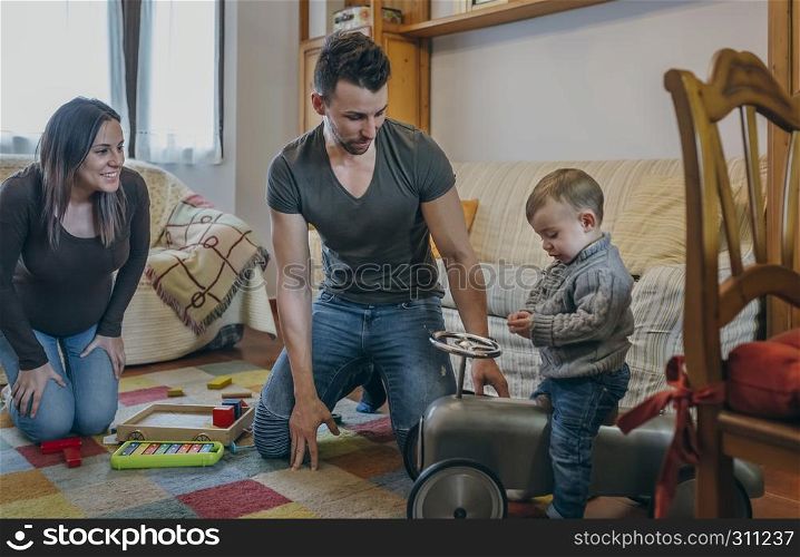 Young parents and their little son playing with a vintage little race car. Parents and their little son playing with a little race car