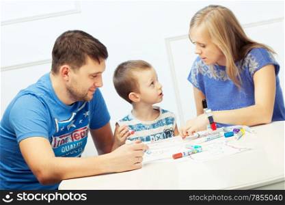 Young parents drawing at the table with their son