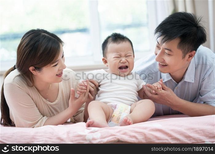 Young parents playing with their baby on the bed