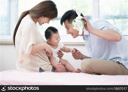 Young parents playing with their baby on the bed
