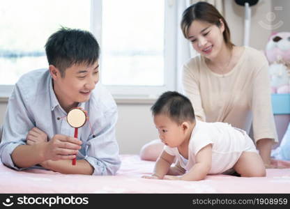 Young parents playing with their baby on the bed