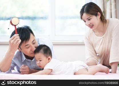 Young parents playing with their baby on the bed