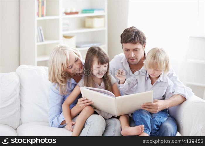 Young parents read the book to children at home