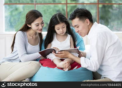 Young parents reading a book with their daughter