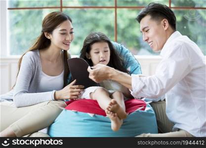 Young parents reading a book with their daughter