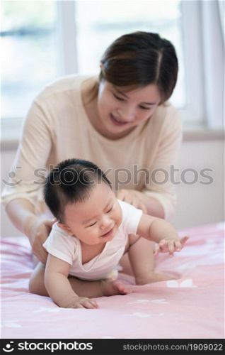 Young parents taking care of her baby on the bed