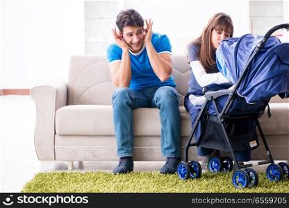 Young parents with their newborn baby in baby pram sitting on th. Young parents with their newborn baby in baby pram sitting on the sofa