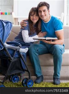 Young parents with their newborn baby in baby pram sitting on the sofa. Young parents with their newborn baby in baby pram sitting on th