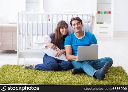 Young parents with their newborn baby sitting on the carpet