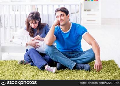 Young parents with their newborn baby sitting on the carpet