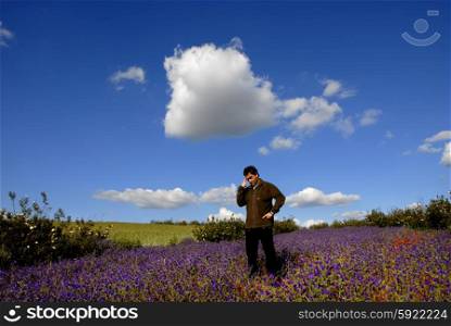 young pensive man among flowers and the sky