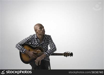 Young pensive man holding guitar
