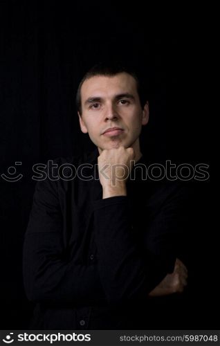 young pensive man portrait, on a black background