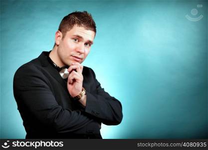 Young pensive man student with headphones copyspace blue background