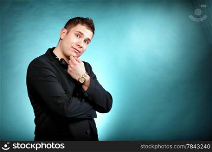 Young pensive man student with headphones copyspace blue background