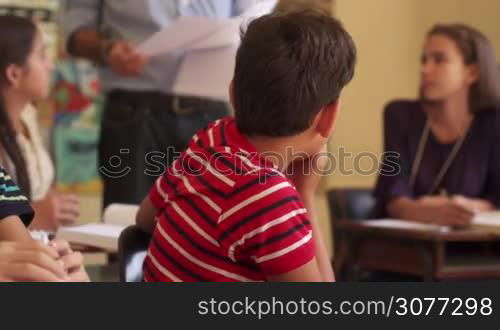 Young people and education. Group of hispanic students in class at school during lesson. Sad male student depressed for bad grades on test, unhappy boy with papers