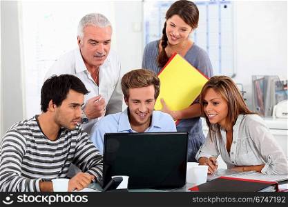 Young people and their manager sitting round a laptop computer