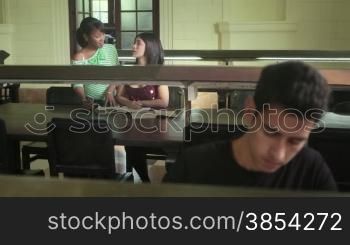 Young people at school, male and female students studying and doing homework in university library